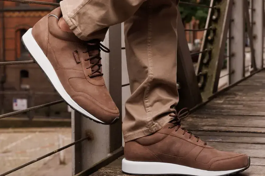Braune Walkingschuhe beim Gehen über eine Holzbrücke