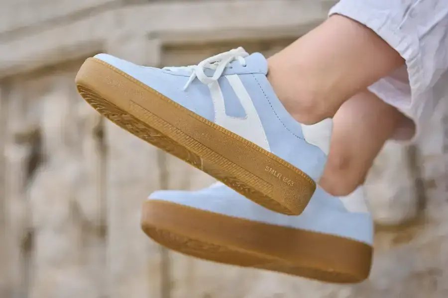 Hellblauer Sneaker mit karamellfarbener Sohle im Schritt