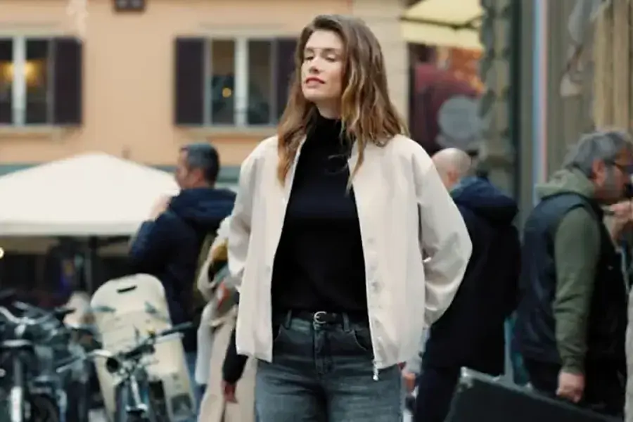 Frau in heller Jacke und Jeans in einer belebten Altstadtgasse